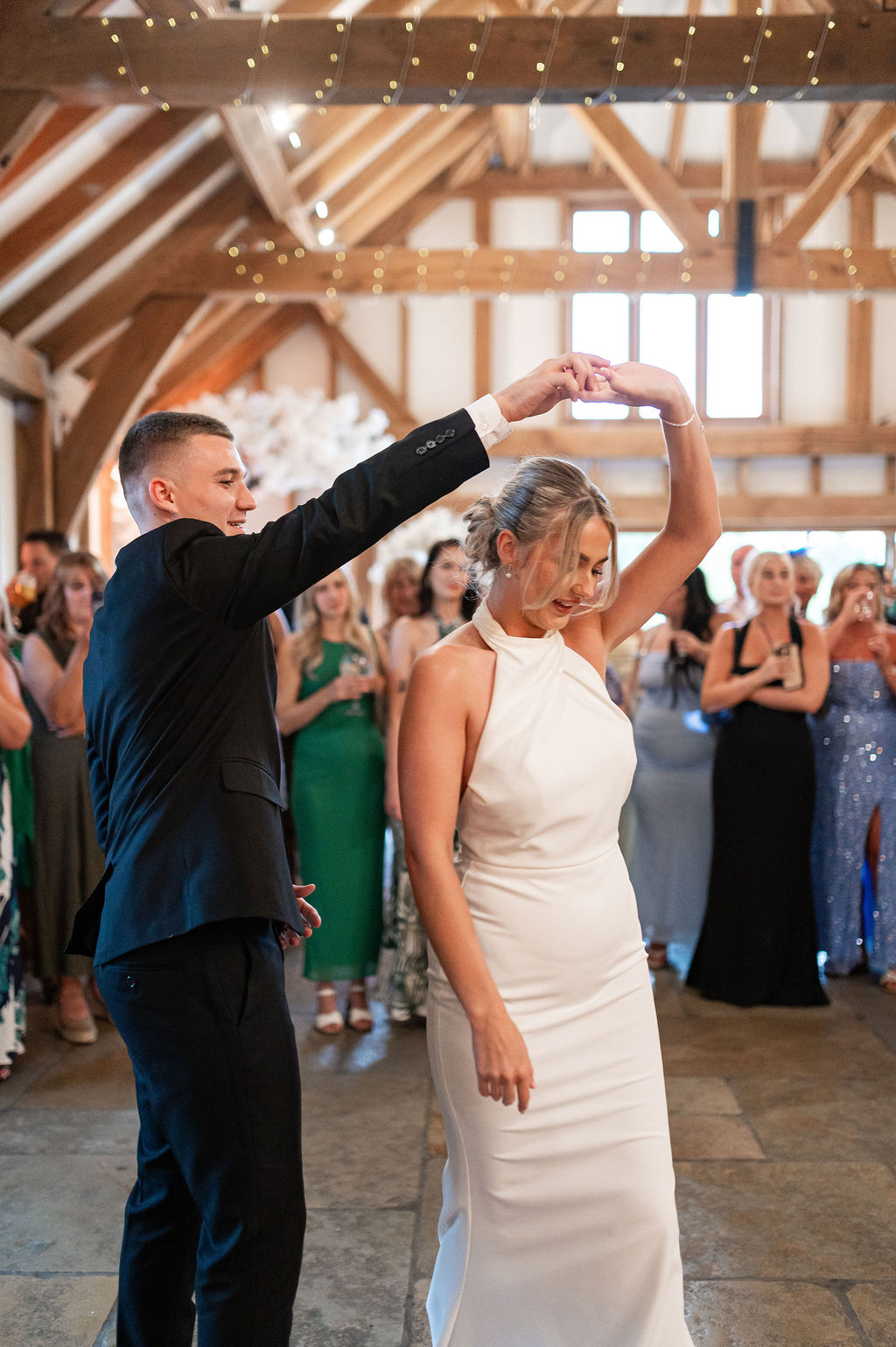 A couple sharing a first-dance twirl, surrounded by their wedding guests